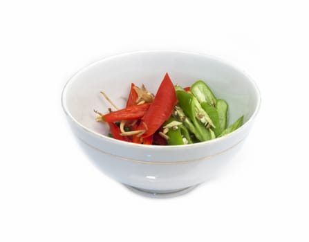 Red and green peppers in a glass cup on a white background