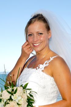 Happy wedding bride is holding a bouquet and is smiling.