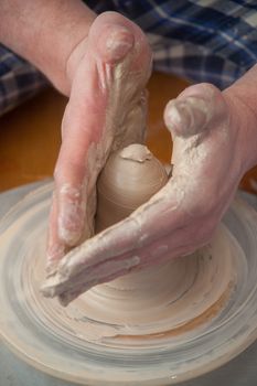 hands of a potter, creating an earthen jar on the circle