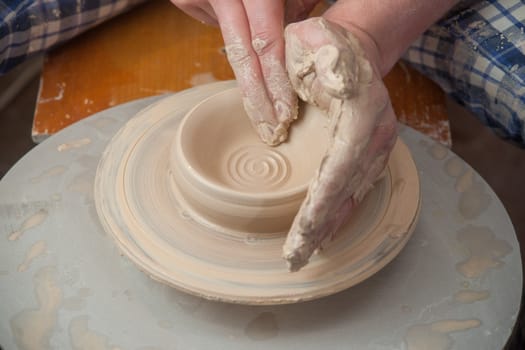 hands of a potter, creating an earthen jar on the circle