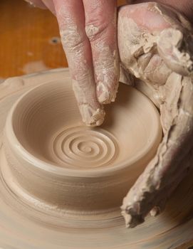 hands of a potter, creating an earthen jar on the circle