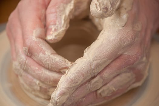 hands of a potter, creating an earthen jar on the circle