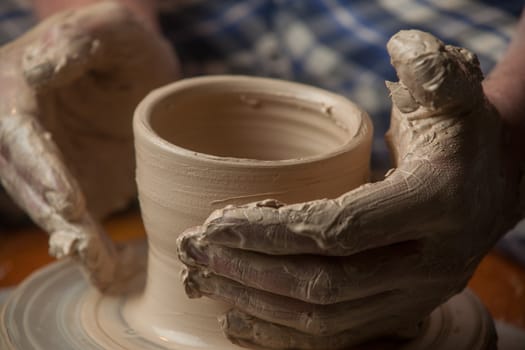 hands of a potter, creating an earthen jar on the circle