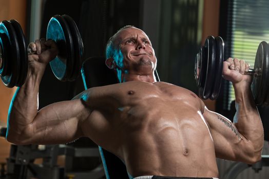 Handsome Young Man Doing Dumbbell Incline Bench Press Workout In Gym