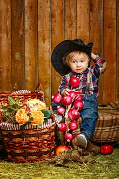 Little Cowboy on a farm in a hat and jeans after harvest