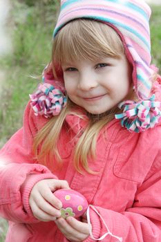 Pretty girl holding painted egg outdoor in spring