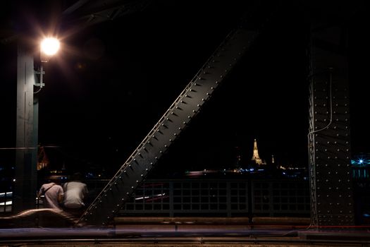 Couple sitting by the road. Under a light one. Romantic at night.