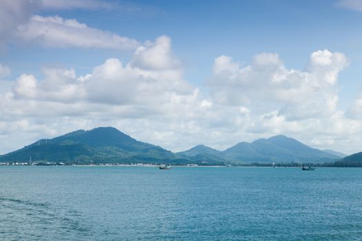 Mountains, sea and sky on a clear day atmosphere. A small boat sailing in the sea.