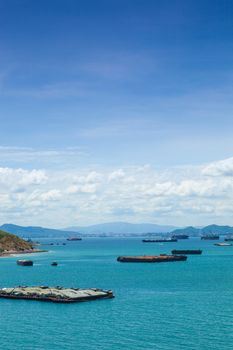 Cargo ships. Moored in the sea near the island. The bright sky in the daytime.