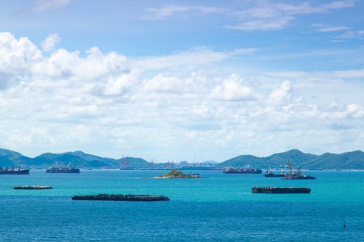 Cargo ships. Moored in the sea near the island. The bright sky in the daytime.