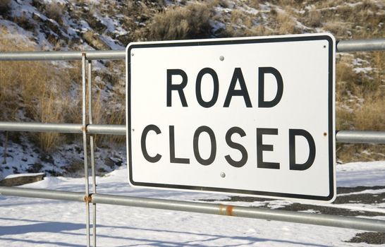 A gate with a sign that says "road closed" found in the dead of winter