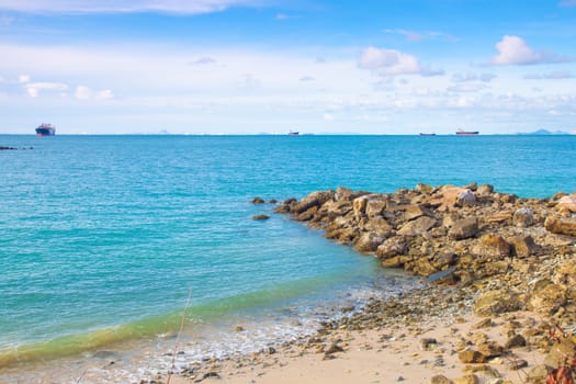 Beach rocks large Cargo ship moored in the sea side of the island.