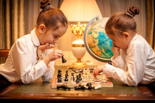 Sisters in school uniform playing chess