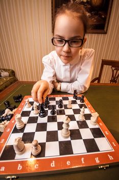 Portrait of girl in eyeglasses playing chess