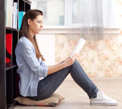 Young smiling student with a lbook in a library