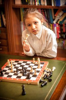 Girl in white shirt thinking on move at chess