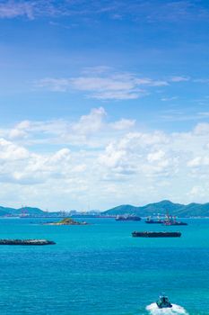 Cargo ships. Moored in the sea near the island. The bright sky in the daytime.