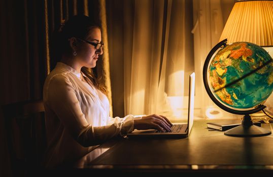 Toned portrait of sexy woman working on laptop at dark room