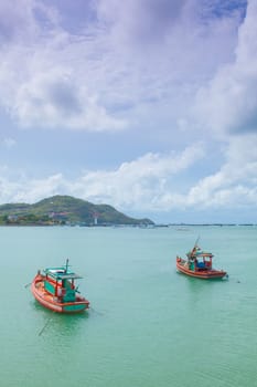 Small fishing boats moored in the sea. Behind the mountains and trees.