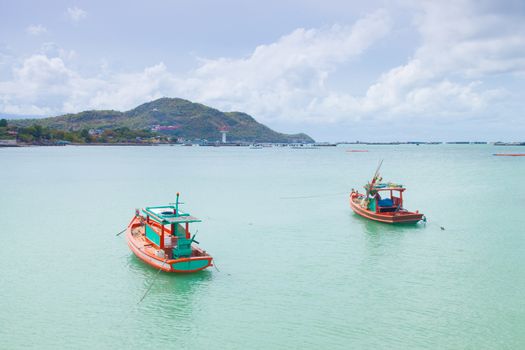 Small fishing boats moored in the sea. Behind the mountains and trees.