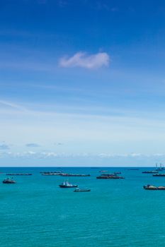 Cargo ships. Moored offshore. In the daytime sky with little clouds.