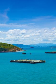 Cargo ships. Moored in the sea near the island. The bright sky in the daytime.