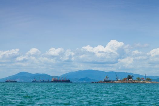 cargo ship Moored near the island behind a mountain.