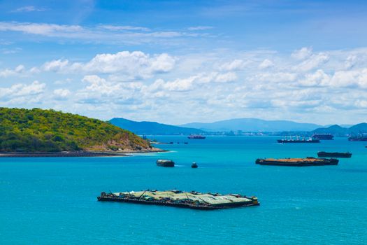 Cargo ships. Moored in the sea near the island. The bright sky in the daytime.