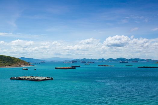 Cargo ships. Moored in the sea near the island. The bright sky in the daytime.