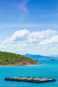Cargo ships. Moored in the sea near the island. The bright sky in the daytime.