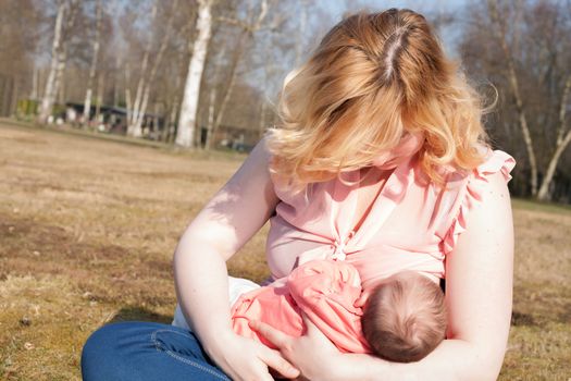 Mother is feeding her baby on the field