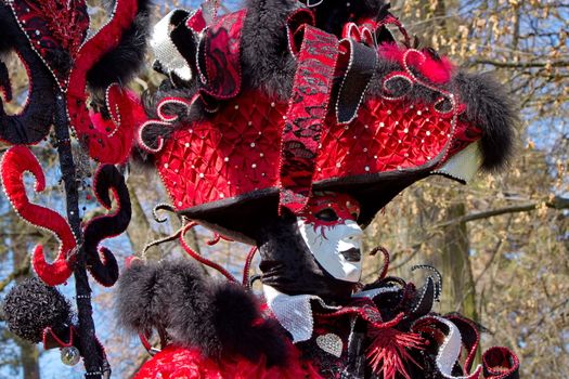 Red and black person with big hat at the 2014 venetian carnival of Annecy, France