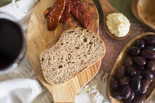 Slice of fresh whole wheat bread with olives, hummus and sun dried tomatoes.