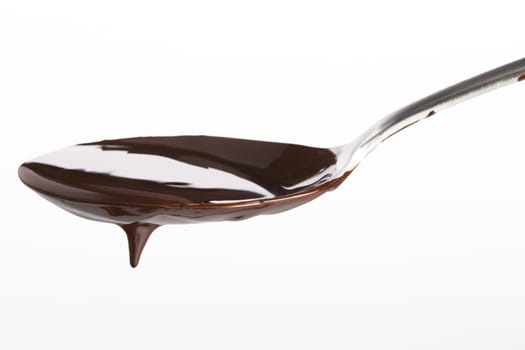Spoon of melted chocolate topping on white background