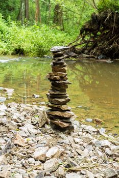 Stones pyramid near small river symbolizing zen, harmony, balance