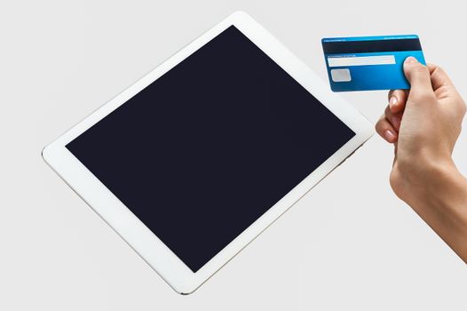 Hand holding credit card and tablet pc on a grey background