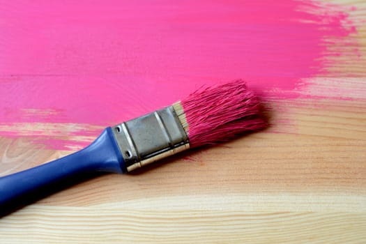 Pine wood half-painted with dirty paintbrush