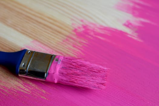 Dirty paintbrush on half-painted wooden surface