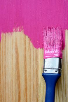 Closeup of pine plank being painted in a bright colour, with copy space