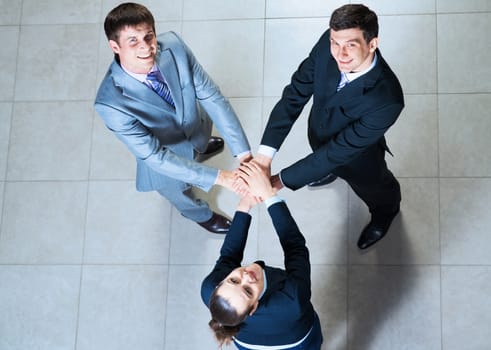 team of three businessmen with folded hands, a symbol of teamwork