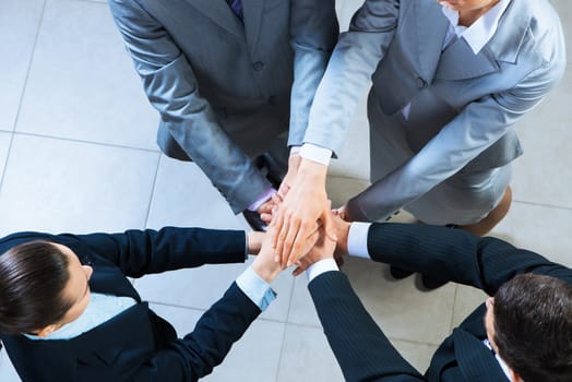 team of four businessmen with folded hands, a symbol of teamwork