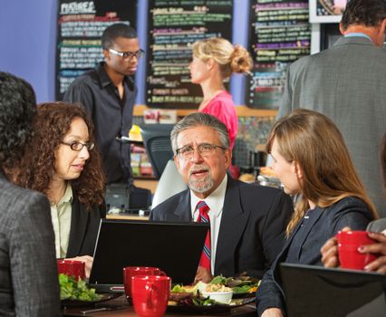 Group of diverse executives eating lunch in cafeteria