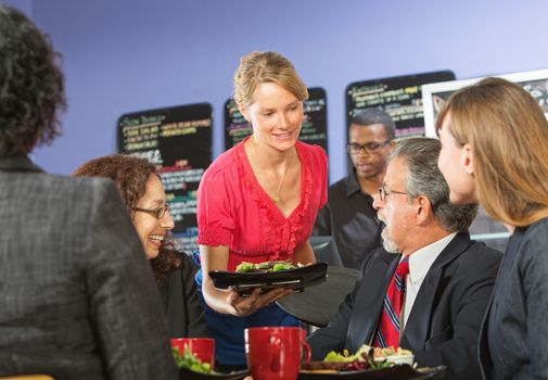 Young barista serving smiling executives food in cafe