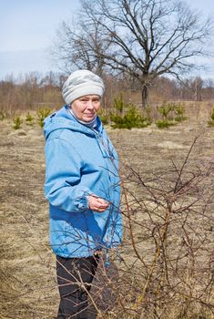 Elderly woman in a spring forest walks one