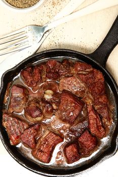 Oven Baked Beef Cubes in Cast Iron Skillet at table or restaurant.