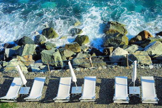 Deck chair at a rocky beach. Mediterranean sea, Italy