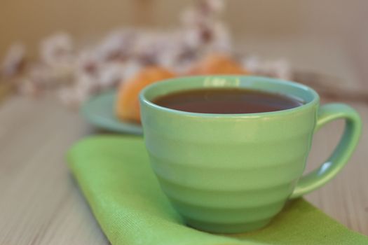 Cup of tea and croissants near blossoming branches. toning