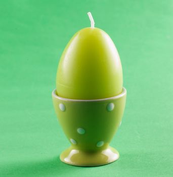 Green candle in shape of egg over green