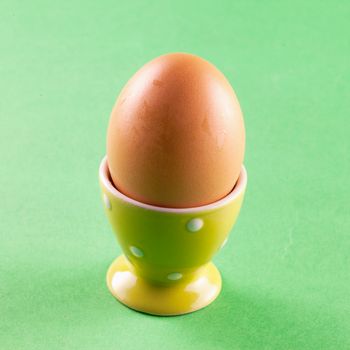 Egg in eggcup over a green background