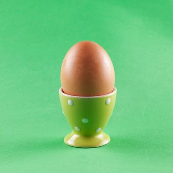Egg in eggcup over a green background